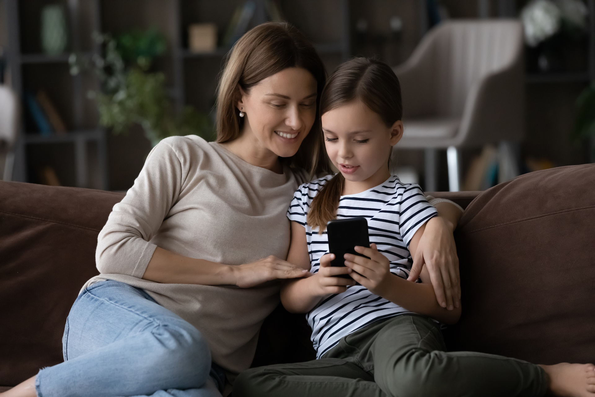 Mama i córka wspólnie przeglądają telefon, planując kontakt podczas rozłąki na obozie letnim, co pomaga złagodzić uczucie tęsknoty.